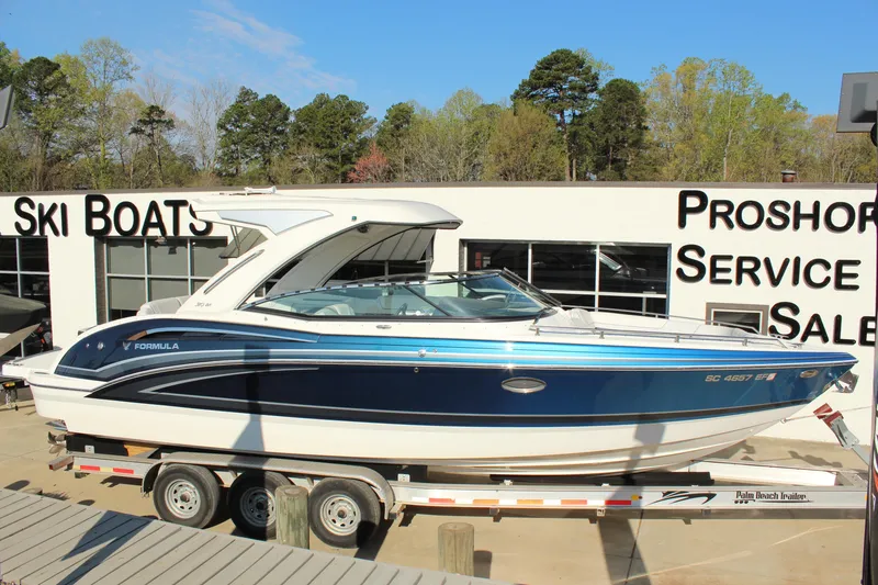 Slide: The Image of 2023 Formula 310 Bowrider I/O boat on trailer at dealership, sunny day. - 8