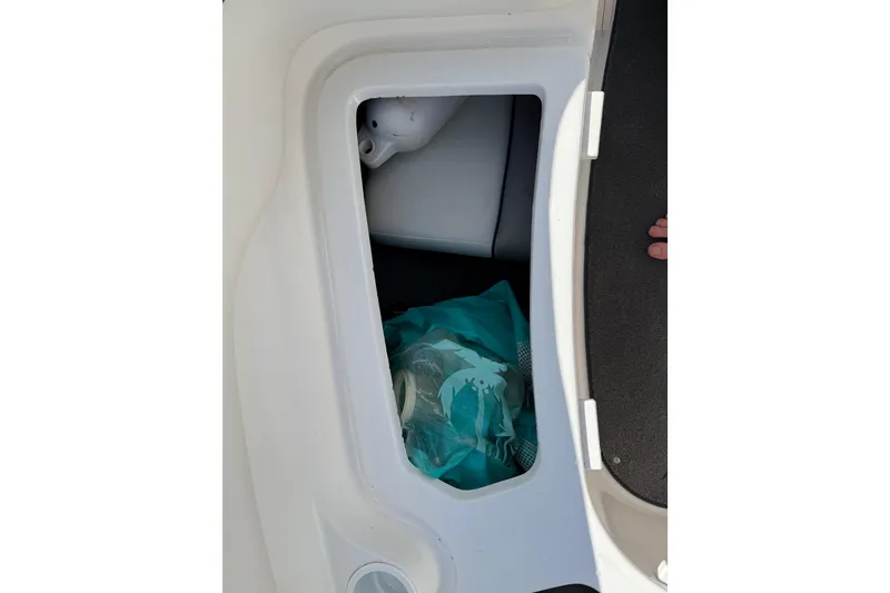 Slide: The Image of Storage compartment in a 2005 Yamaha Boats SX230, containing a teal bag and white object. - 40