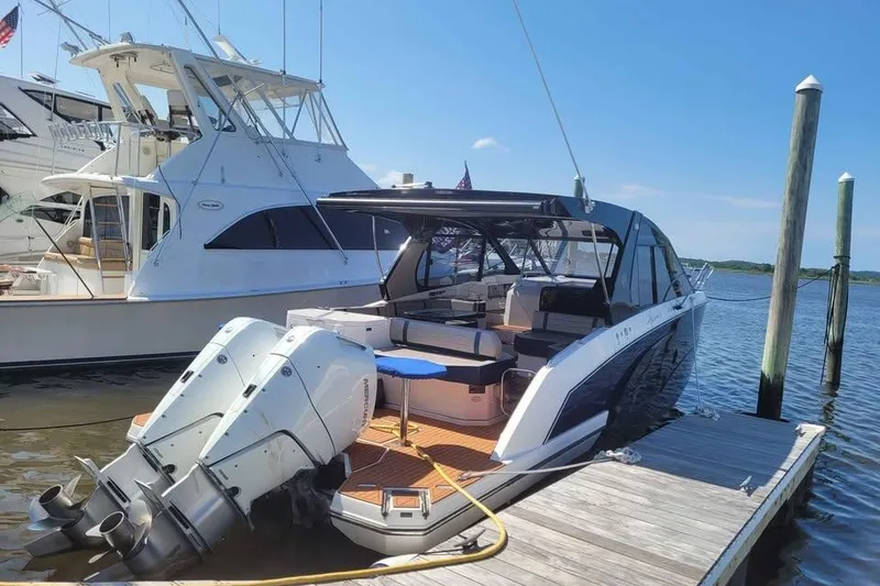 Slide: The Image of 2024 Hanover 387 boat docked, featuring dual outboard motors and sleek design. - 2