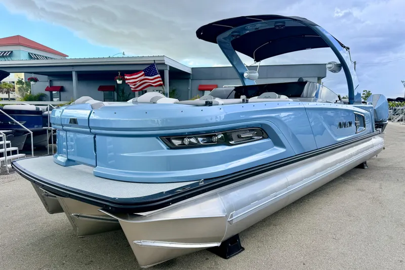 The Image of 2026 Avalon 2 pontoon boat in light blue, docked with American flag in background. - 1