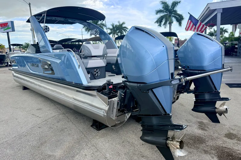Slide: The Image of 2026 Avalon 2 pontoon boat with dual outboard motors, parked outdoors. - 12