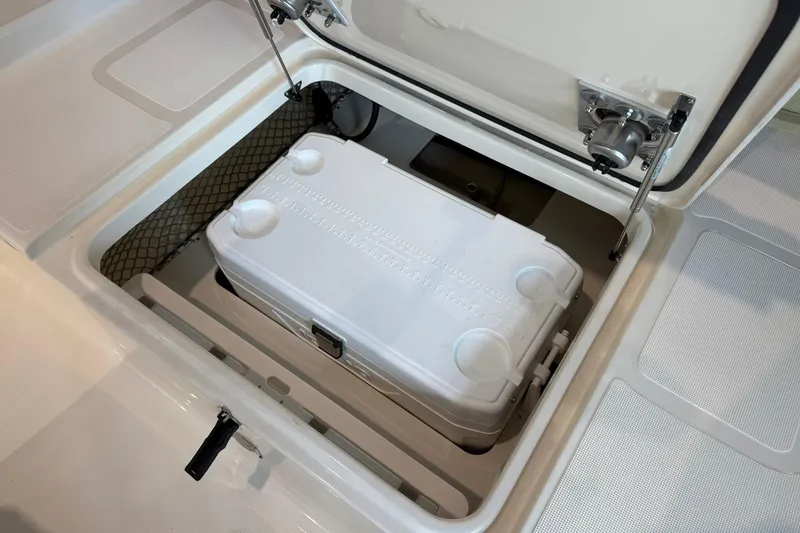 Slide: The Image of 2026 Scout 177 XSS boat storage compartment with white cooler inside. - 11