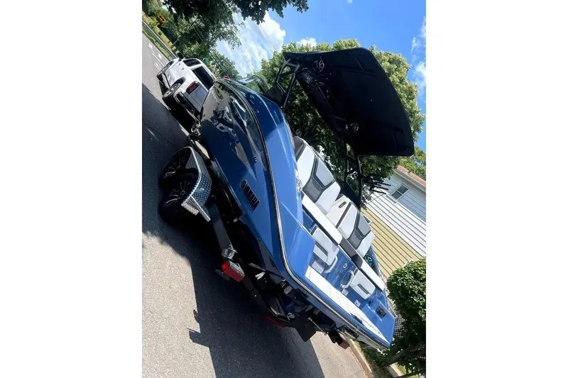 Slide: The Image of 2024 Yamaha Boats 255XE in blue, parked on a sunny street. - 5