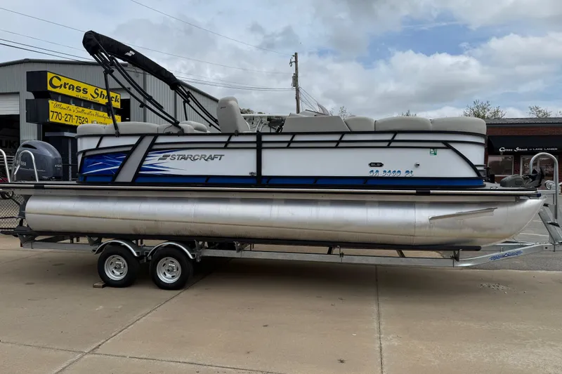 Slide: The Image of 2022 Starcraft SLS 3 pontoon boat on trailer, parked outside dealership. - 2