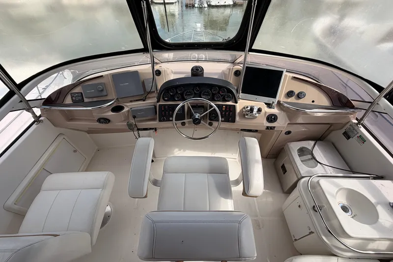 Slide: The Image of 2005 Carver 41 Cockpit Motor Yacht helm with steering wheel, controls, and seating. - 13