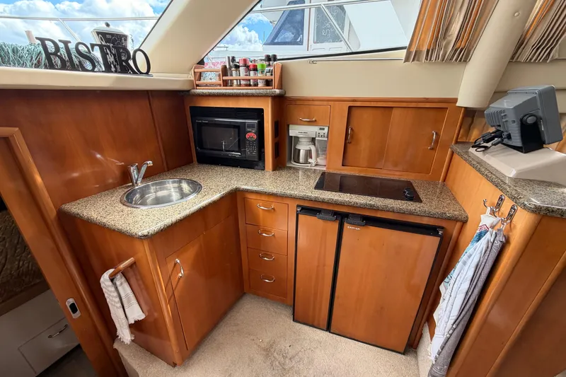 Slide: The Image of Luxurious 2005 Carver 41 Cockpit Motor Yacht kitchen with modern amenities and wood cabinetry. - 23