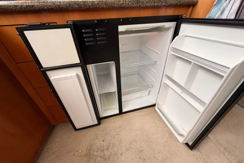 Slide: The Image of Open refrigerator inside a 2005 Carver 41 Cockpit Motor Yacht, showing empty shelves and compartments. - 24