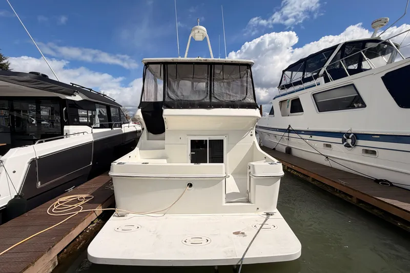 Slide: The Image of 2005 Carver 41 Cockpit Motor Yacht docked between two boats under a blue sky. - 3