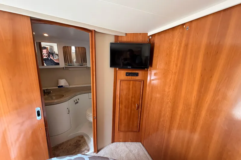 Slide: The Image of 2005 Carver 41 Cockpit Motor Yacht interior with wood paneling, TV, and bathroom view. - 30