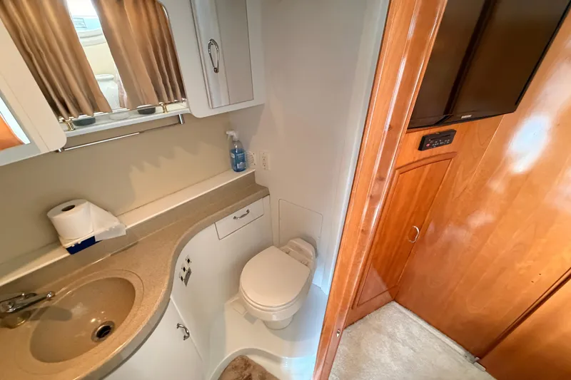 Slide: The Image of 2005 Carver 41 Cockpit Motor Yacht bathroom with sink, toilet, and wooden cabinetry. - 31