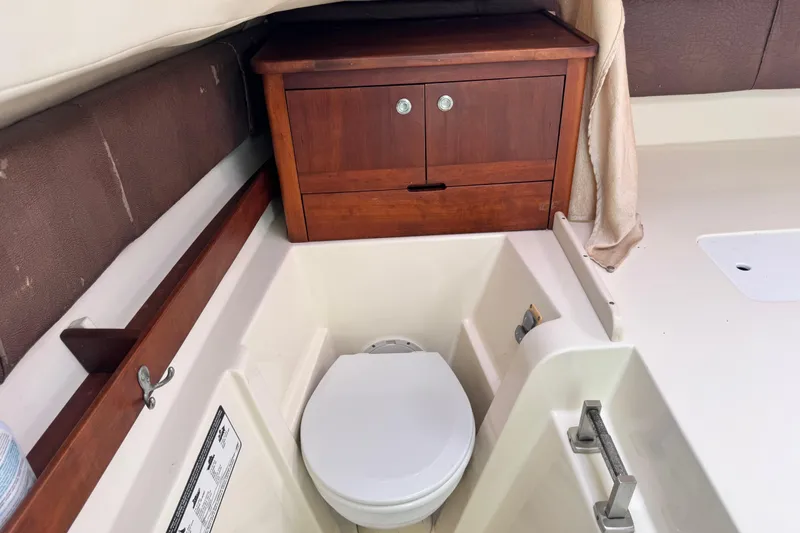 Slide: The Image of 2011 Glacier Bay 2670 Cuddy boat interior with toilet and wooden cabinet. - 27