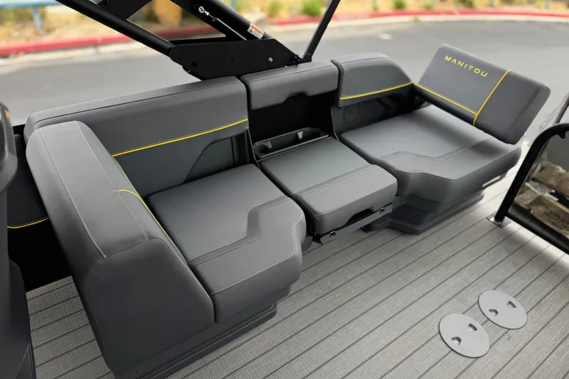 Slide: The Image of 2025 Manitou EXPLORE 24 boat interior with sleek gray seating and yellow accents. - 15