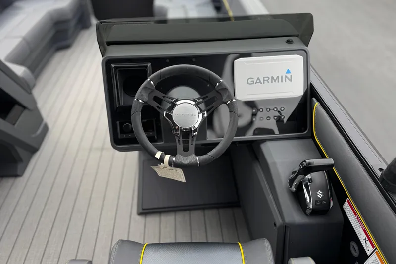 Slide: The Image of 2025 Manitou EXPLORE 24 boat dashboard with Garmin navigation system and steering wheel. - 23