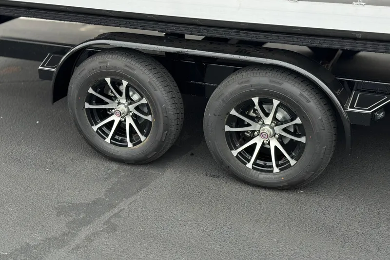 Slide: The Image of Dual wheels of a 2025 Manitou EXPLORE 24 trailer on asphalt surface. - 24