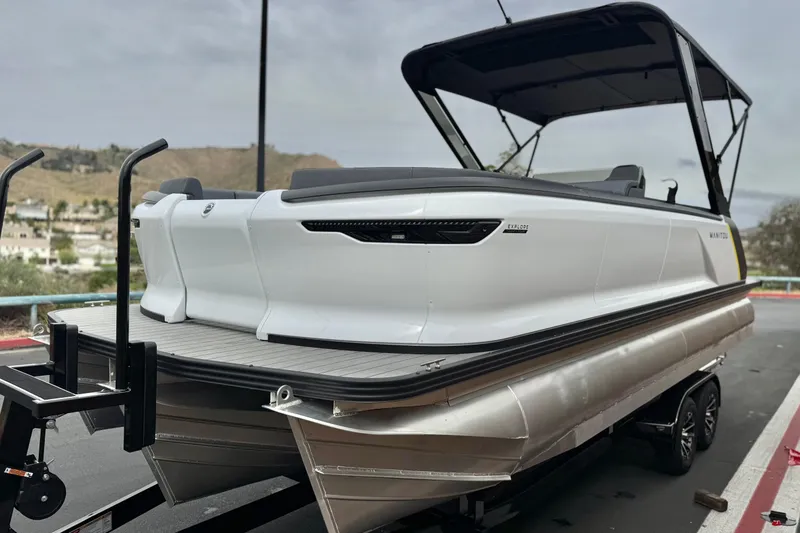 Slide: The Image of 2025 Manitou EXPLORE 24 pontoon boat on trailer, sleek design, outdoor setting. - 3