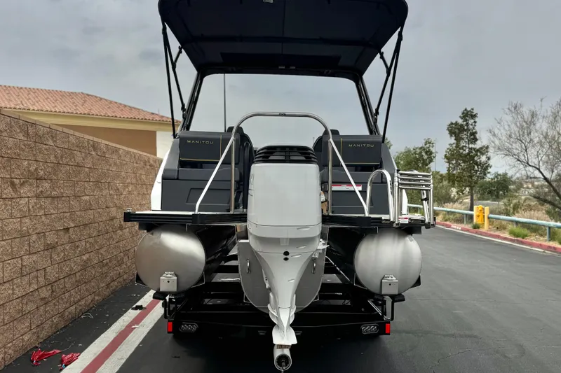 Slide: The Image of 2025 Manitou EXPLORE 24 pontoon boat with outboard motor, parked on a paved road. - 5