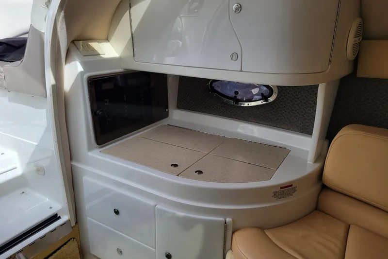 Slide: The Image of Interior of a 2002 Cobalt 293 boat, featuring a compact kitchenette and seating area. - 22