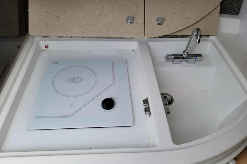 Slide: The Image of Compact kitchen area in a 2002 Cobalt 293 boat with stove and sink. - 24