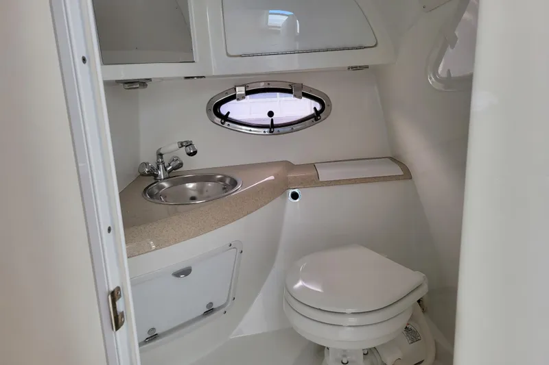 Slide: The Image of Compact bathroom in a 2002 Cobalt 293 boat with sink, toilet, and porthole window. - 29
