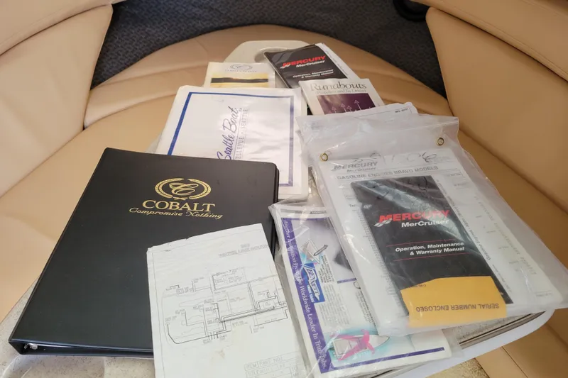 Slide: The Image of Collection of manuals and documents for a 2002 Cobalt 293 boat on a beige seat. - 35