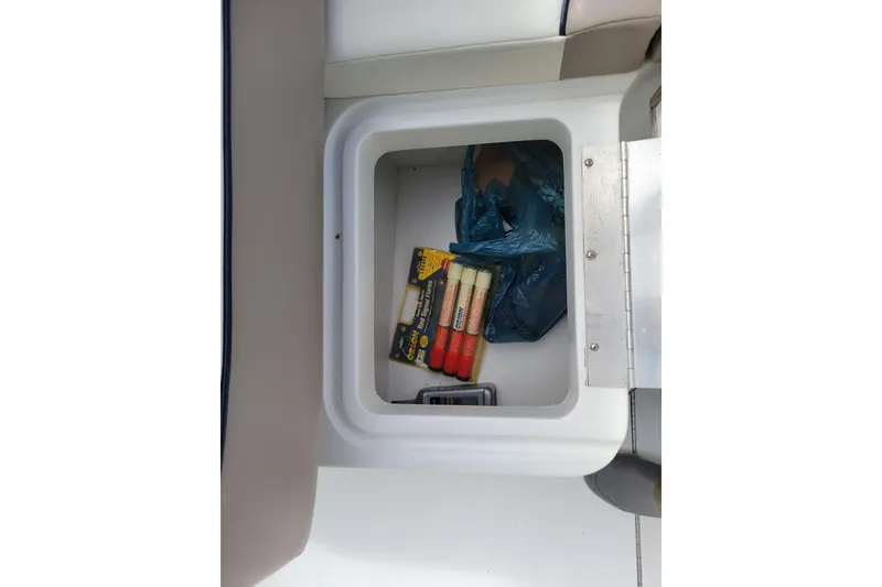 Slide: The Image of Storage compartment in a 2002 Cobalt 293 boat with safety flares and a plastic bag. - 37