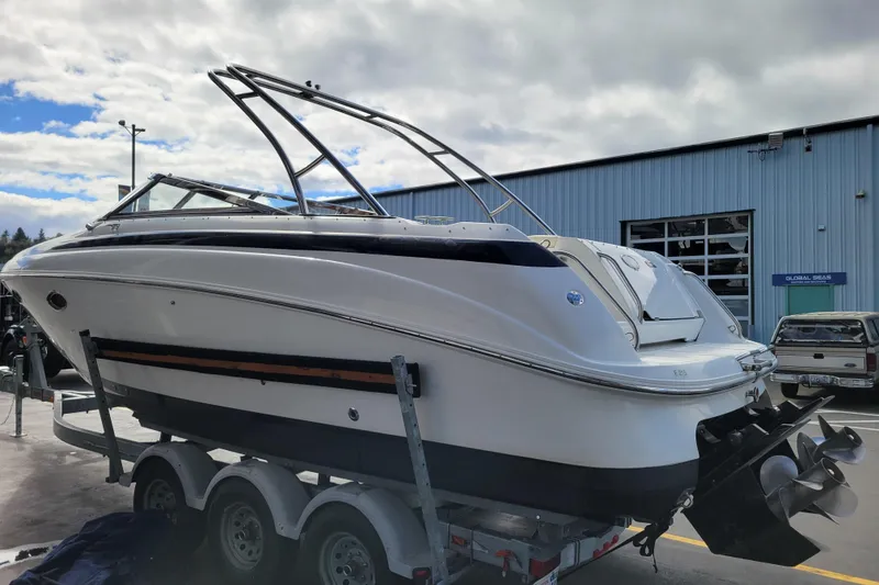 Slide: The Image of 2002 Cobalt 293 boat on trailer, parked outside a blue industrial building. - 4