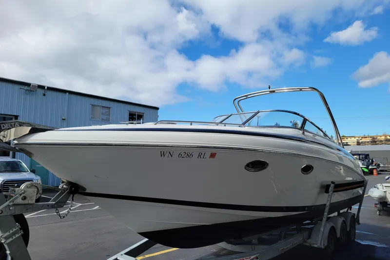 Slide: The Image of 2002 Cobalt 293 boat on trailer under blue sky, parked near industrial building. - 5
