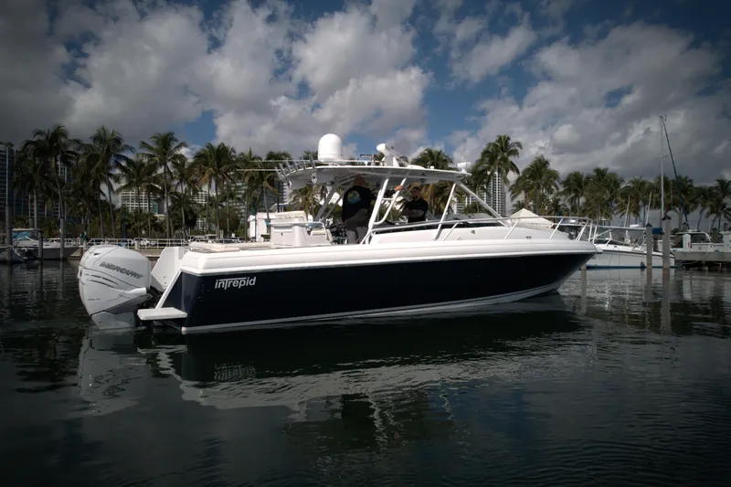 Slide: The Image of 2002 Intrepid 377 Walkaround Cuddy boat docked in a marina with palm trees. - 11