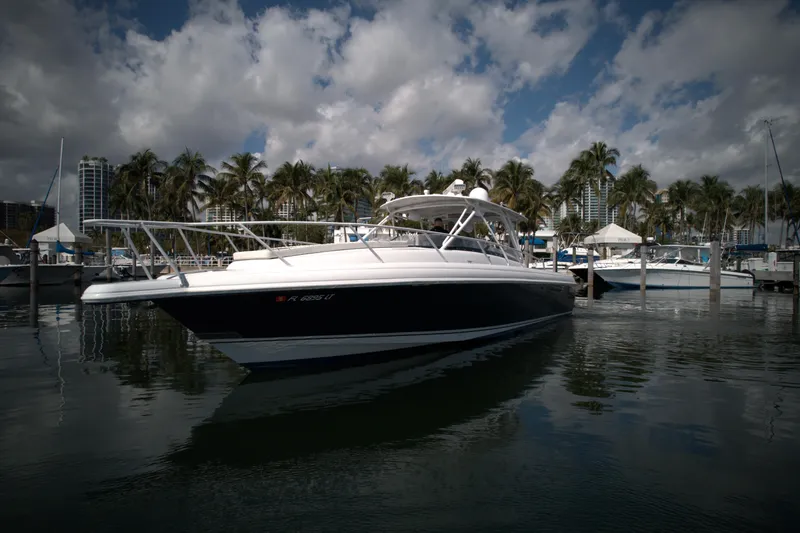 Slide: The Image of 2002 Intrepid 377 Walkaround Cuddy boat docked in a marina with palm trees. - 3