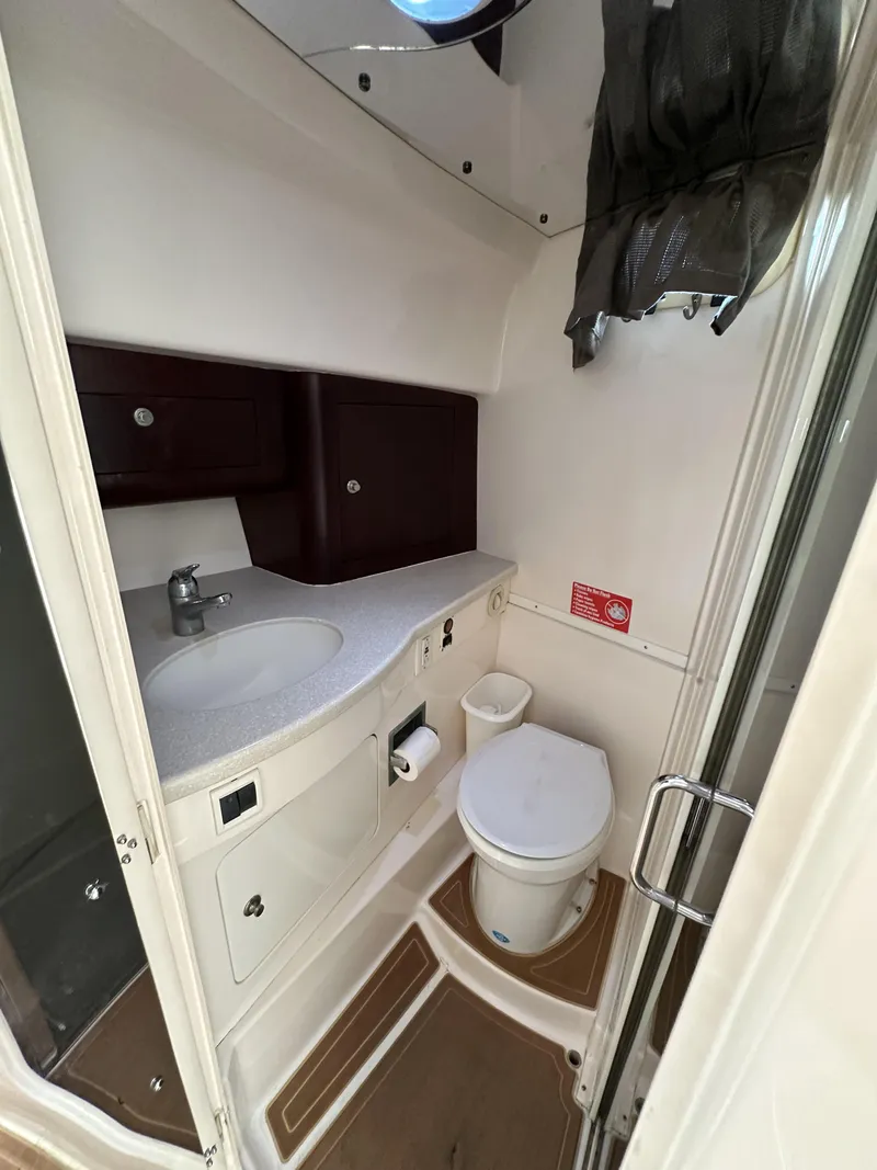 Slide: The Image of 2002 Intrepid 377 Walkaround Cuddy bathroom with sink, toilet, and storage cabinets. - 39