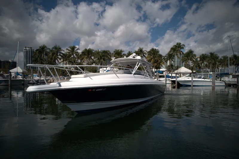 Slide: The Image of 2002 Intrepid 377 Walkaround Cuddy boat docked in a marina with palm trees. - 4