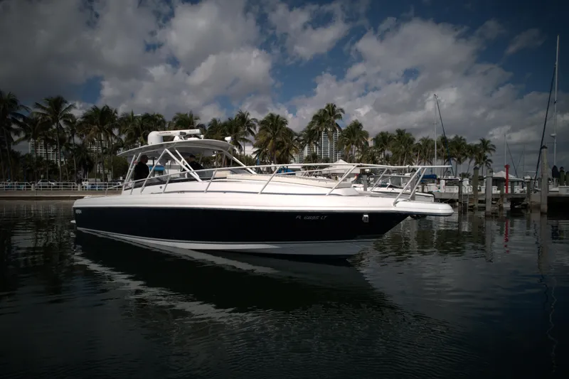 Slide: The Image of 2002 Intrepid 377 Walkaround Cuddy boat docked in a marina with palm trees. - 8