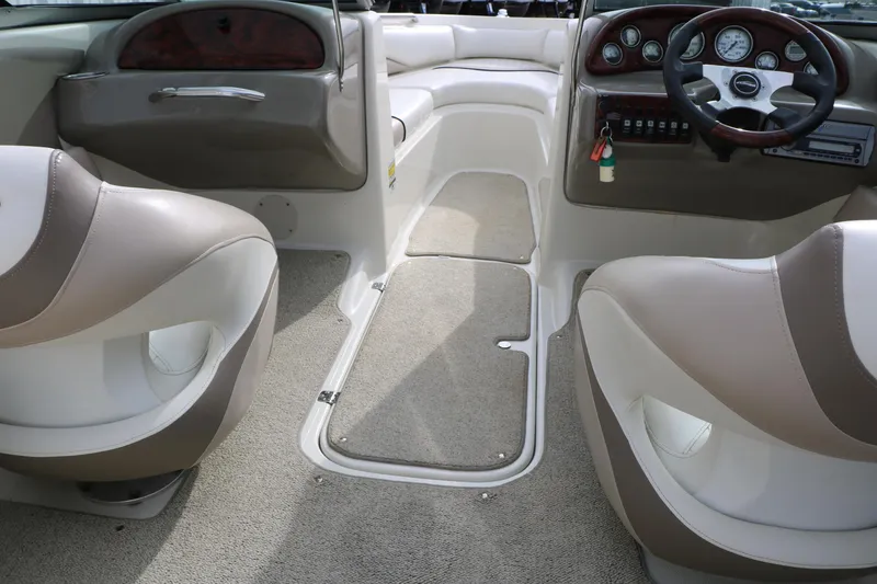 Slide: The Image of Interior of a 2006 Caravelle 207 Bow Rider boat, featuring beige seating and dashboard controls. - 24