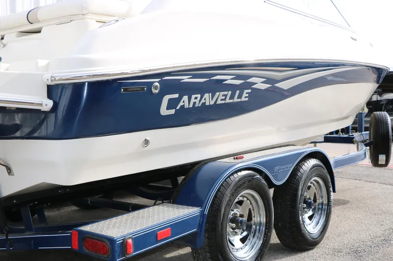 Slide: The Image of 2006 Caravelle 207 Bow Rider boat on a trailer, featuring sleek blue and white design. - 8