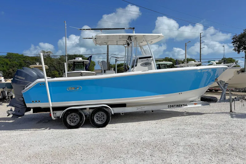 The Image of 2011 Sea Hunt Gamefish 25 boat on trailer, vibrant blue hull, Yamaha engine, sunny day. - 1