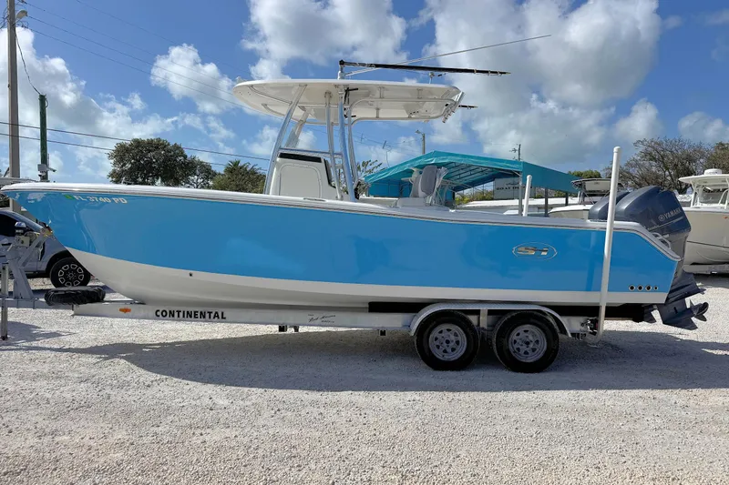 Slide: The Image of 2011 Sea Hunt Gamefish 25 boat on trailer, blue hull, parked outdoors under cloudy sky. - 4