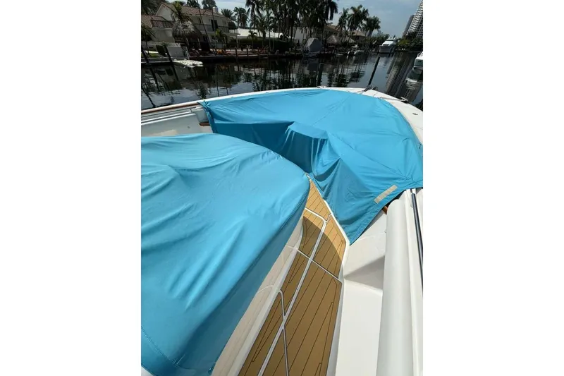 Slide: The Image of 2021 HCB 65 Estrella boat with blue covers docked by waterfront homes. - 105