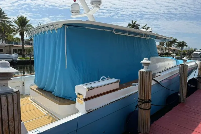Slide: The Image of 2021 HCB 65 Estrella yacht docked, covered with a blue tarp, surrounded by palm trees. - 106