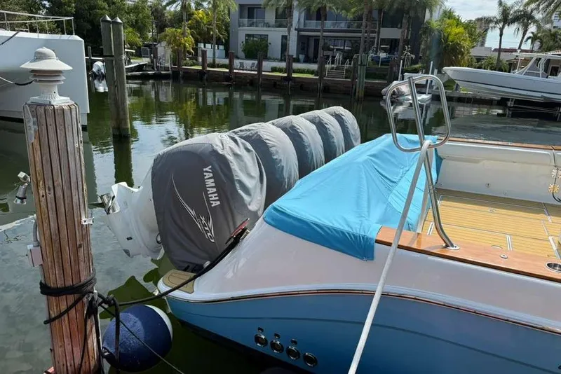 Slide: The Image of 2021 HCB 65 Estrella boat docked with Yamaha engines, covered in blue tarp. - 107