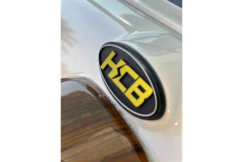 Slide: The Image of HCB 65 Estrella 2021 logo on sleek white surface with wood detail. - 53