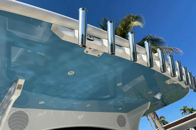Slide: The Image of 2021 HCB 65 Estrella boat with rod holders and blue canopy under clear sky. - 64