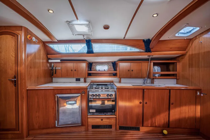Slide: The Image of Interior of 2003 Jeanneau Sun Odyssey 45.2 yacht, featuring a wooden kitchen galley. - 45