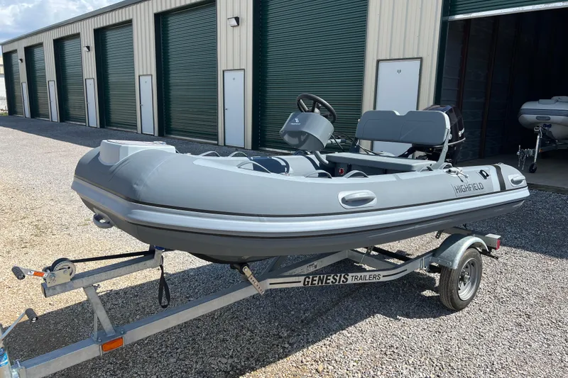 The Image of 2026 Highfield Classic 340 FCT inflatable boat on Genesis trailer, parked near storage units. - 8