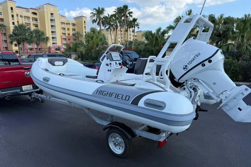 Slide: The Image of 2026 Highfield Sport 420 inflatable boat with Tohatsu engine on trailer, parked near palm trees. - 5