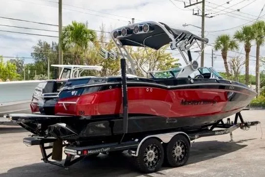 The Image of 2019 MasterCraft XStar boat on trailer, red and black design, parked outdoors. - 1