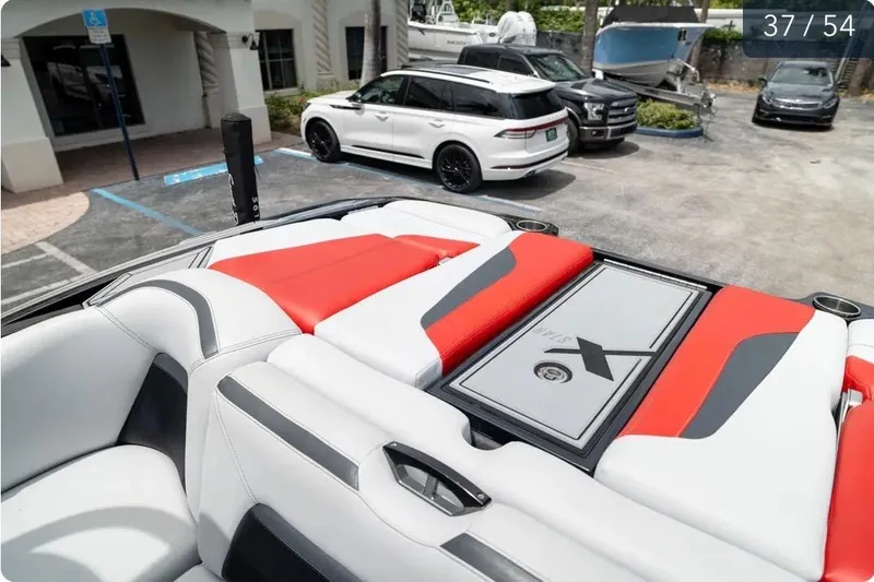 Slide: The Image of 2019 MasterCraft XStar boat interior with red and white seating, parked cars in the background. - 10