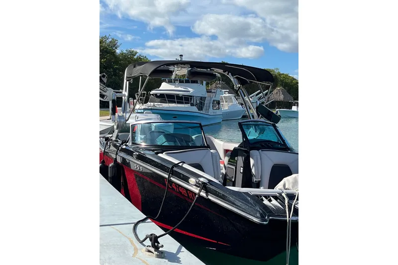 Slide: The Image of 2019 MasterCraft XStar boat docked, featuring sleek black and red design under a clear sky. - 18