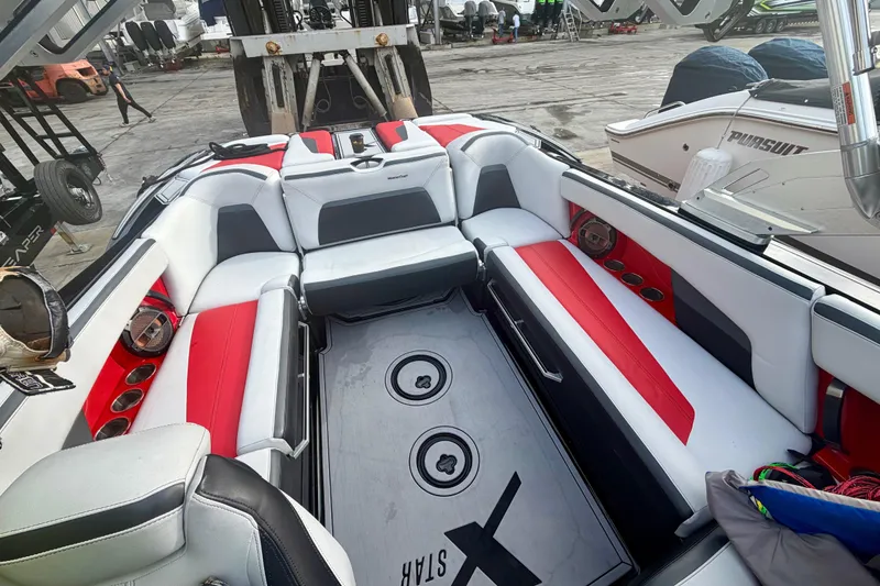 Slide: The Image of 2019 MasterCraft XStar boat interior with red and white seating, docked at a marina. - 3