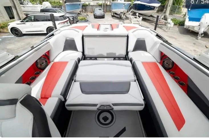 Slide: The Image of 2019 MasterCraft XStar boat interior with red and white seating, parked among other boats. - 6