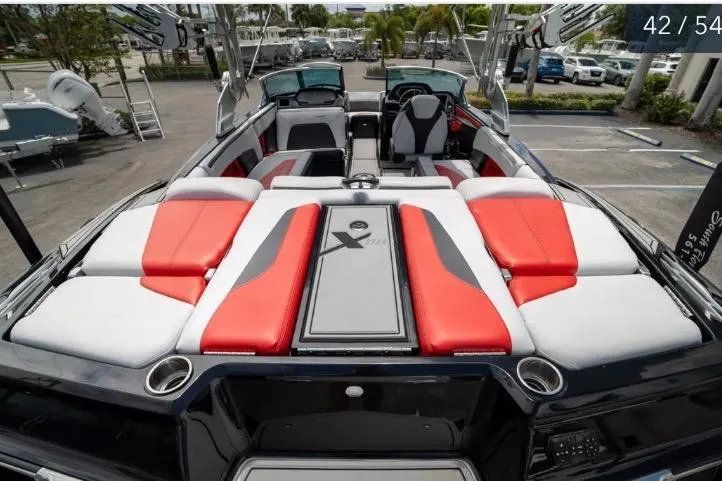 Slide: The Image of 2019 MasterCraft XStar boat interior with red and white seating, parked outdoors. - 9